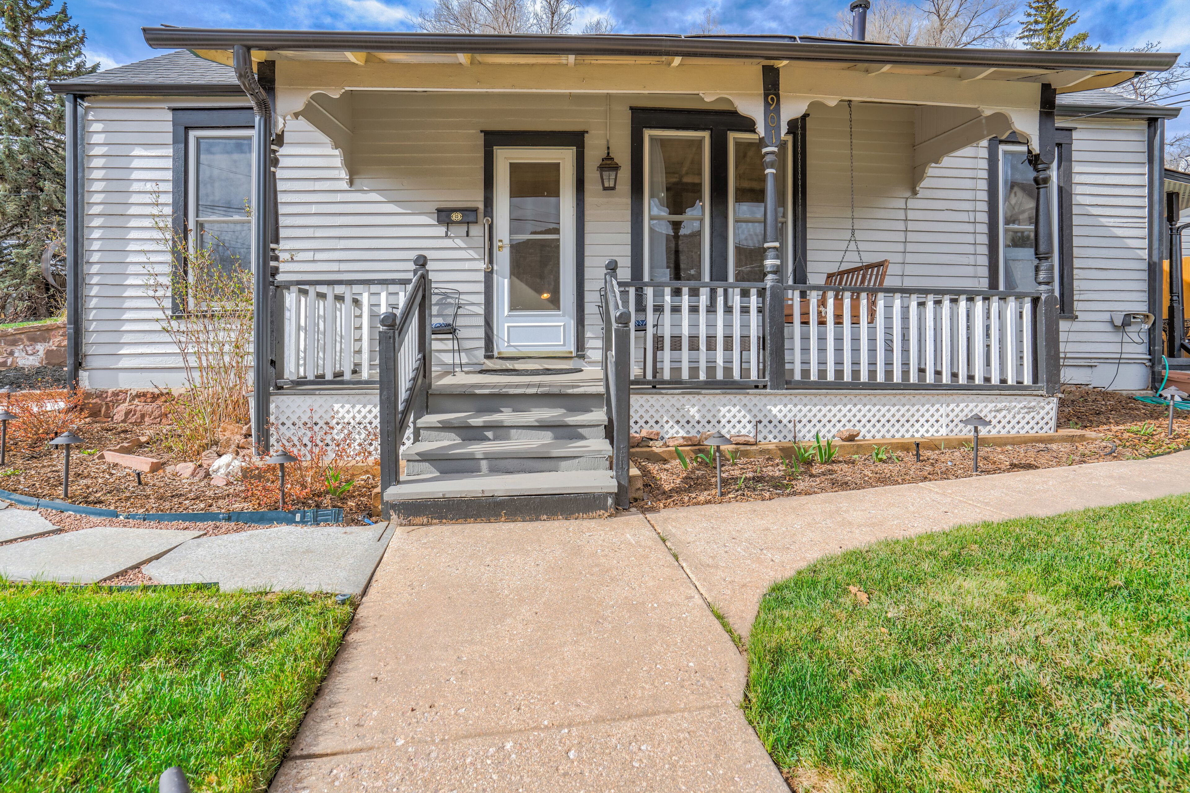 A single-story house with a front porch, a door, and a small set of steps leading to the entrance.