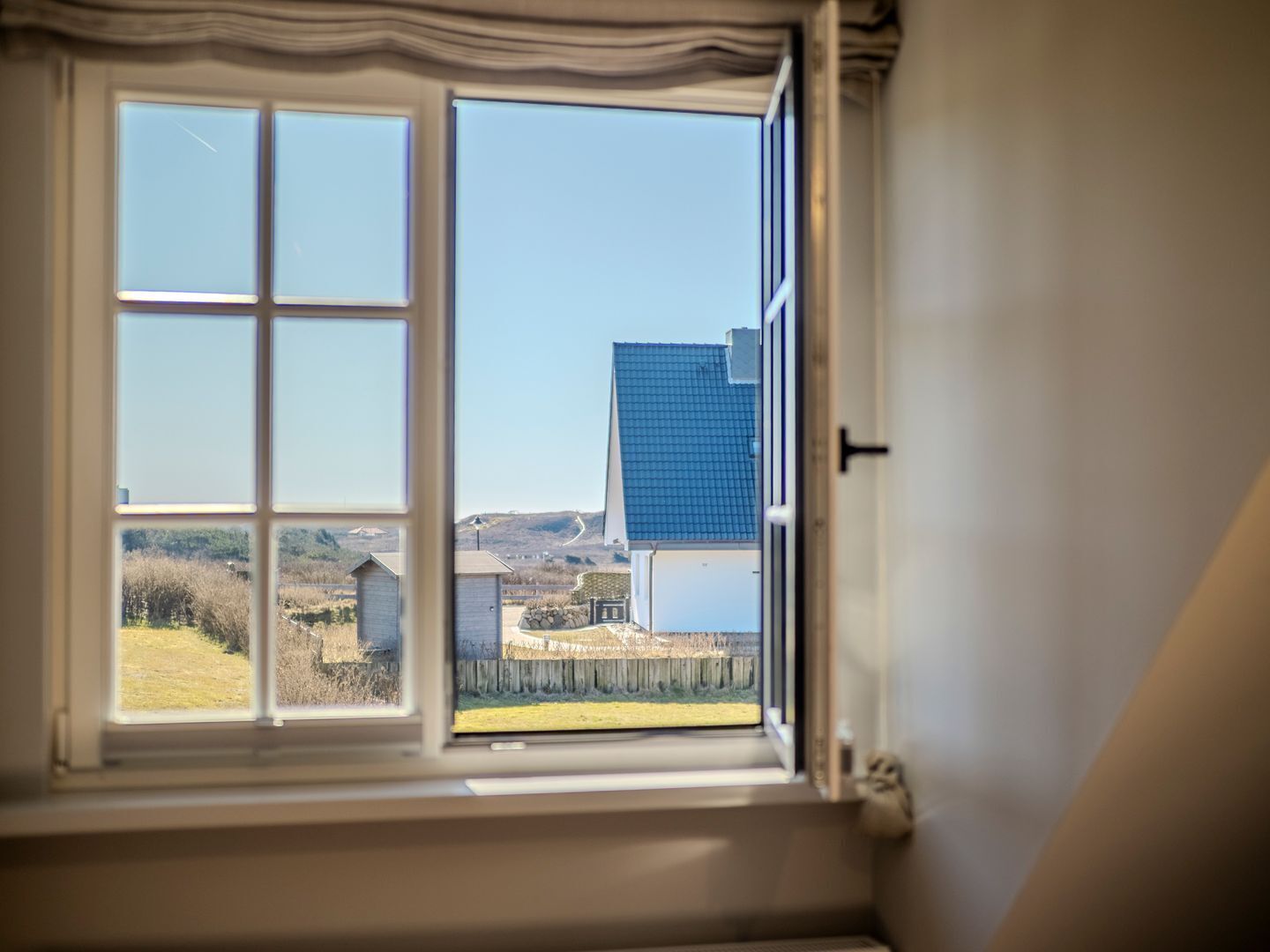 Une fenêtre donnant sur un bâtiment moderne et un paysage rural.