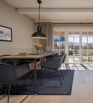 A modern dining area with a wooden table, black chairs, and a black pendant light.