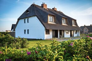 Et stort hvidt hus med et stejlt tag og mange vinduer.