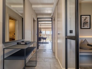 A hallway with a modern design, featuring a built-in bench, a mirror, and a framed artwork on the wall.