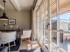 A dining area with a table, chairs, and a hanging light fixture.