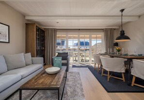A modern living room with a sofa, coffee table, and dining area with chairs and a table.