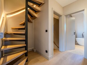 Ein modernes Interieur mit einer Wendeltreppe, einem Badezimmer mit freistehender Badewanne und Holzboden.