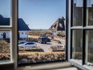 Un pueblo costero con casas tradicionales de techo de paja, un coche aparcado y vistas al mar.