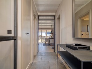 A hallway with a bench, a mirror, and a view into a dining area.