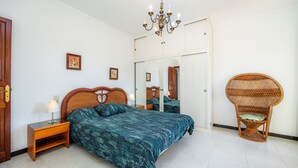 Une chambre à coucher comprenant un lit, une table de chevet, une lampe, une chaise et un miroir.