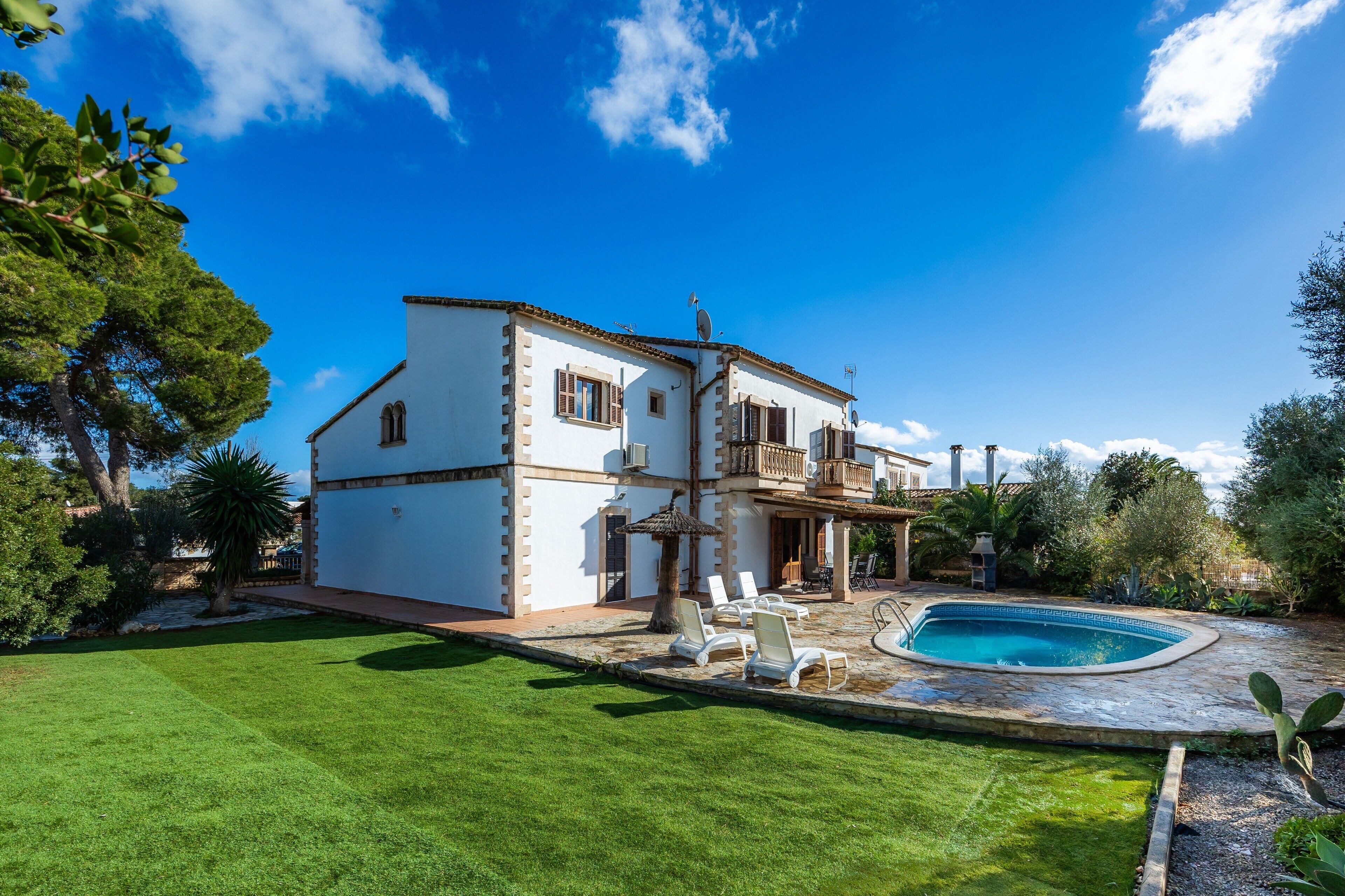 A two-story house with a swimming pool, a well-maintained lawn, and a patio area.