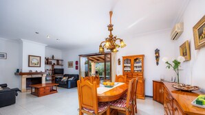 Un salon spacieux comprenant un coin repas, une cheminée et un grand miroir.