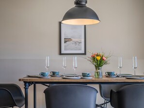 Ein Esstisch gedeckt mit blauen Tassen, Tellern und einer Vase mit Blumen.