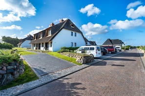 A residential street with houses, a paved driveway, and parked vehicles. - Bohosylt 5 - Exkl. Luxus-hausteil Unter Reet mit 4 Zimmern auf ca. 150 m², für bis zu 6 Pers (Wenningstedt-Braderup (Sylt))