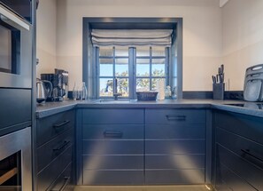 Eine moderne Küche mit einem großen Fenster, Edelstahlgeräten und einer dunklen Arbeitsplatte.