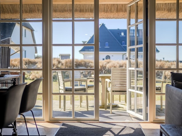 A room with large glass doors leading to an outdoor area with chairs and a table.