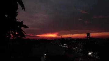 A sunset with a silhouette of a building and trees in the foreground.
