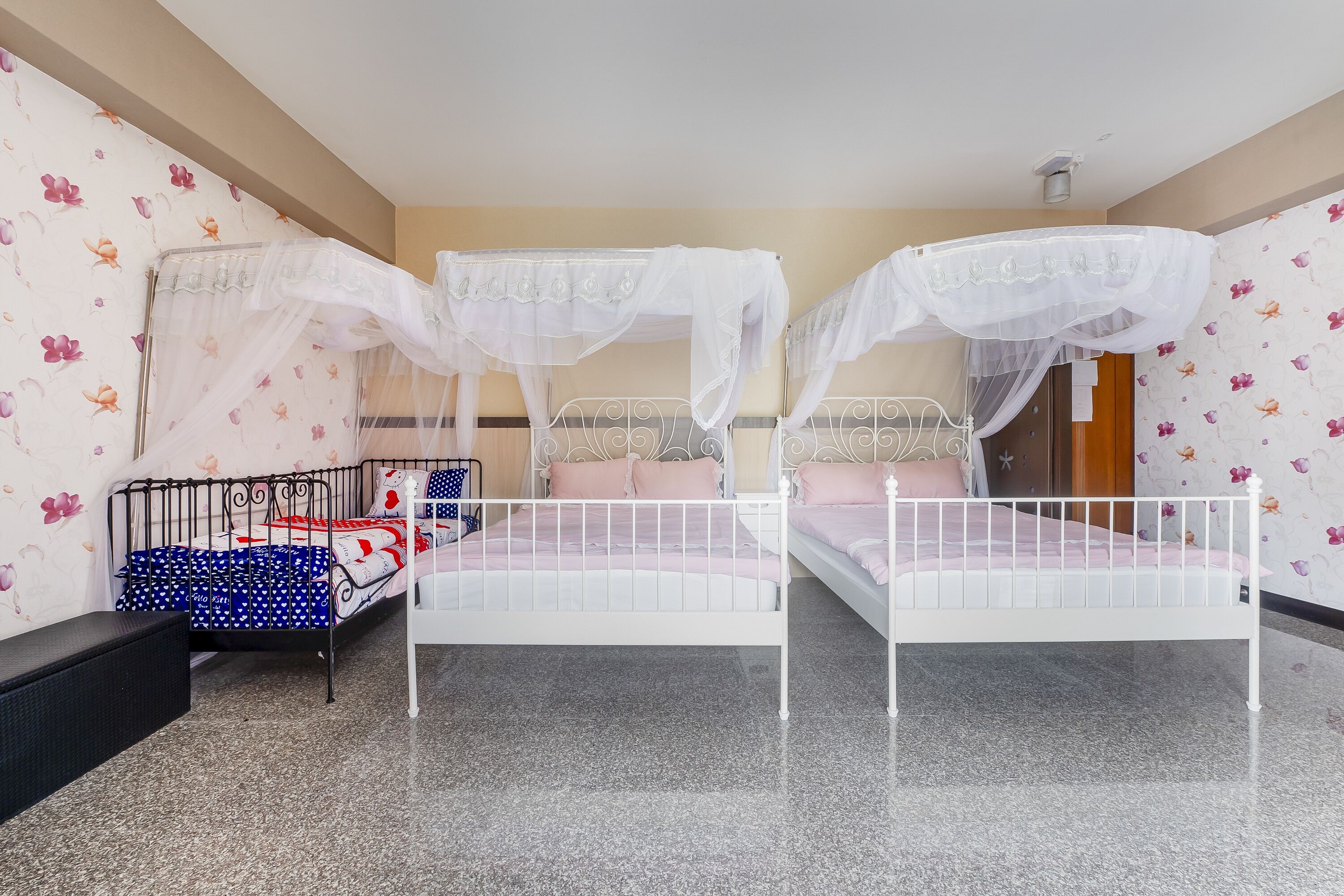 Un dormitorio con dos camas, cada una con dosel blanco, y un banco junto a una cama.