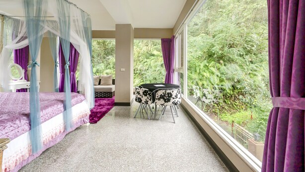 Un dormitorio con cama, una mesita y vistas al verdor exterior.