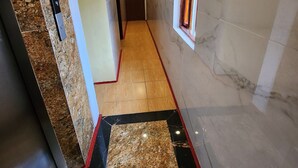 A hotel corridor with marble flooring, a wooden floor section, and a door at the end. - TUAN CENTRAL HOTEL (Hanoi)