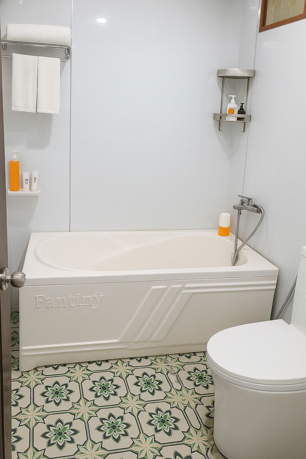 A bathroom with a white bathtub, a toilet, and a sink. There are toiletries on the wall and a showerhead.
