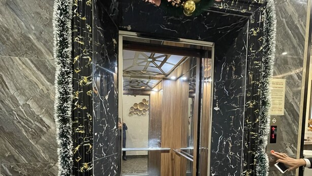 An elevator with a black marble finish, a decorative garland, and a ceiling with a geometric design. - TUAN CENTRAL HOTEL (Hanoi)