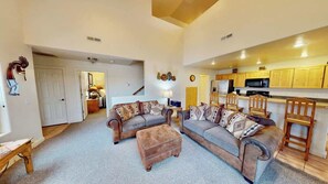 A spacious living area with a sofa set, a coffee table, and a kitchen in the background. - Rim Vistas - 4A4 (Moab)
