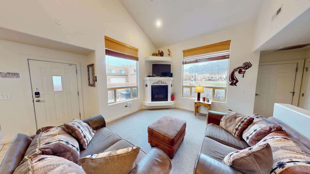 A living room with a fireplace, leather sofas, and a view of the city.