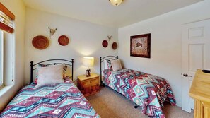 A bedroom with two beds, a bedside table with a lamp, and decorative wall art. - Rim Vistas - 4A4 (Moab)