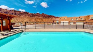Une piscine offrant une vue dégagée sur les bâtiments environnants et avec une chaîne de montagnes en toile de fond.