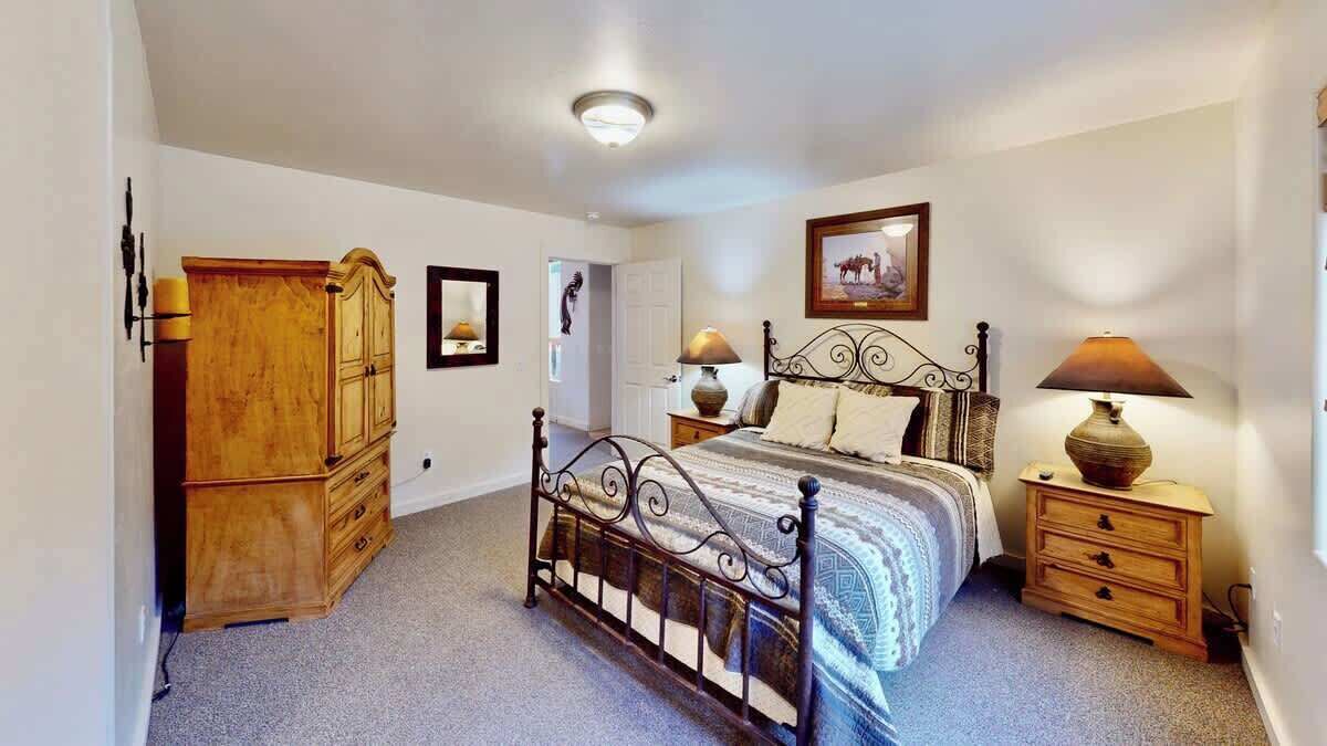 Ein Schlafzimmer mit einem Metallbettgestell, einer Holzkammer, Nachttischlampen und einem gerahmten Bild an der Wand.
