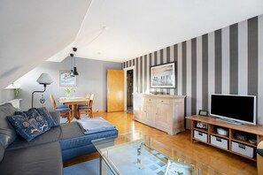 Ett modernt vardagsrum med en soffa, en tv och ett träskåp.