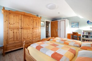 Ein Schlafzimmer mit zwei Betten, einem Holzschrank, einem Schreibtisch und einem Bücherregal.