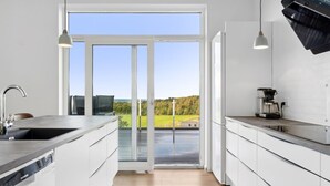 A modern kitchen with white cabinets, a built-in dishwasher, and a coffee maker.