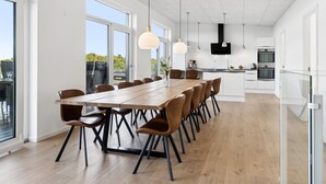 A modern kitchen with a large island, built-in appliances, and a dining area with a long table and chairs.