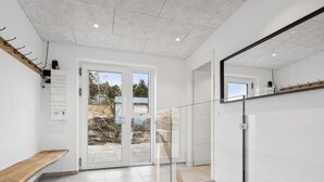 A modern interior with a glass door leading outside, a wooden bench, and a staircase.