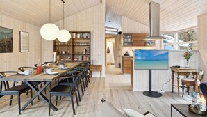 Ein modernes Interieur mit einer Essecke aus Holz, einer Küche und einem Wohnbereich.