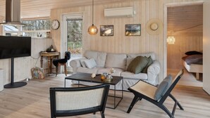Ein gemütliches Blockhausschlafzimmer mit Holzbalkendecke, einer Couch, einem Couchtisch, einem Fernseher und einem Essbereich.
