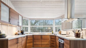 Eine moderne Küche mit Holzschränken, einem großen Fenster und einer Edelstahl-Dunstabzugshaube.