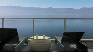 A balcony with two chairs and a round table, overlooking a calm body of water and distant mountains. - Da Li Yu Jia Ren Hotel (Dali)