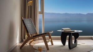 A room with a view of mountains, a wooden chair, a small table with a book, and a glass of orange juice. - Da Li Yu Jia Ren Hotel (Dali)