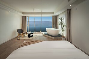Un dormitorio moderno con una cama grande, una bañera y vistas al mar.