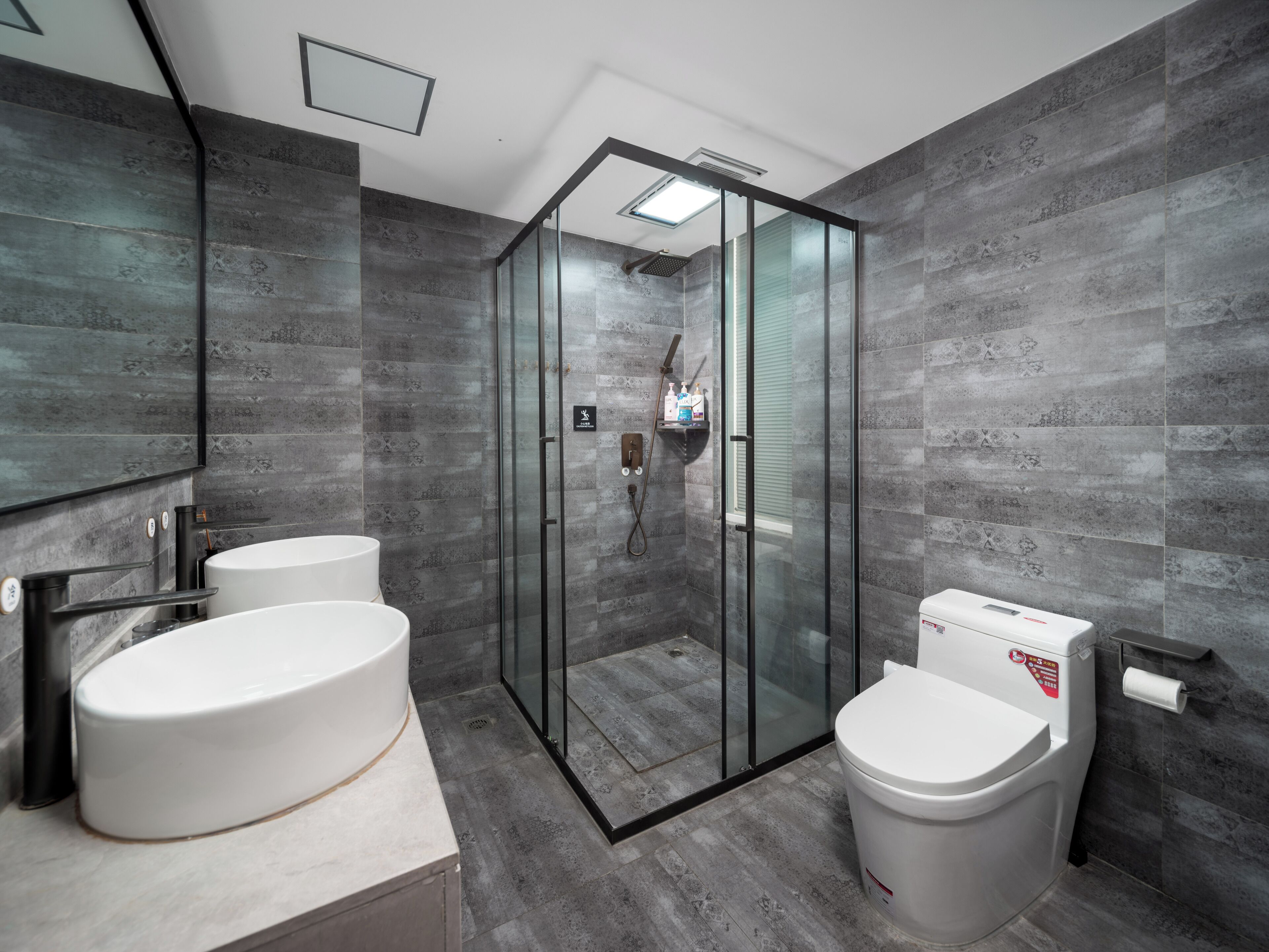 A modern bathroom with a glass-enclosed shower, two sinks, and a toilet.