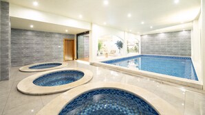 A modern indoor swimming pool area with three circular hot tubs and a larger rectangular pool. - Da Li Yu Jia Ren Hotel (Dali)