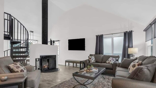 A modern living room with a fireplace, a staircase, and a large window with curtains. - Downtown 2BD Retreat-Walk Everywhere! (Park City)