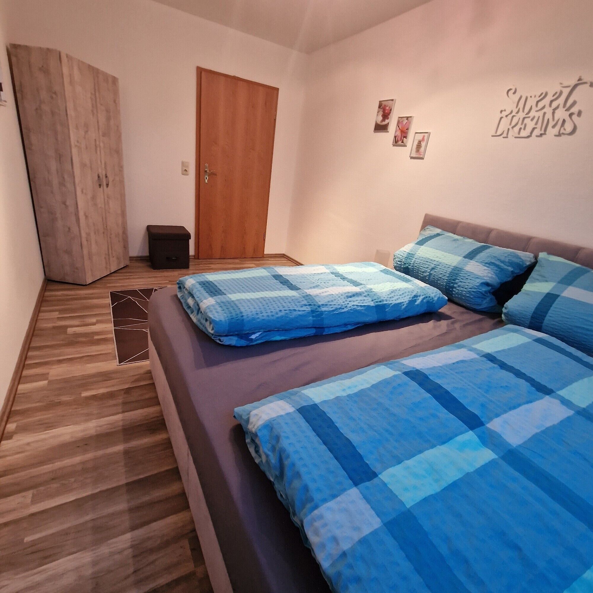 Een slaapkamer met een bed, een kast, een deur en een muur met een bord.