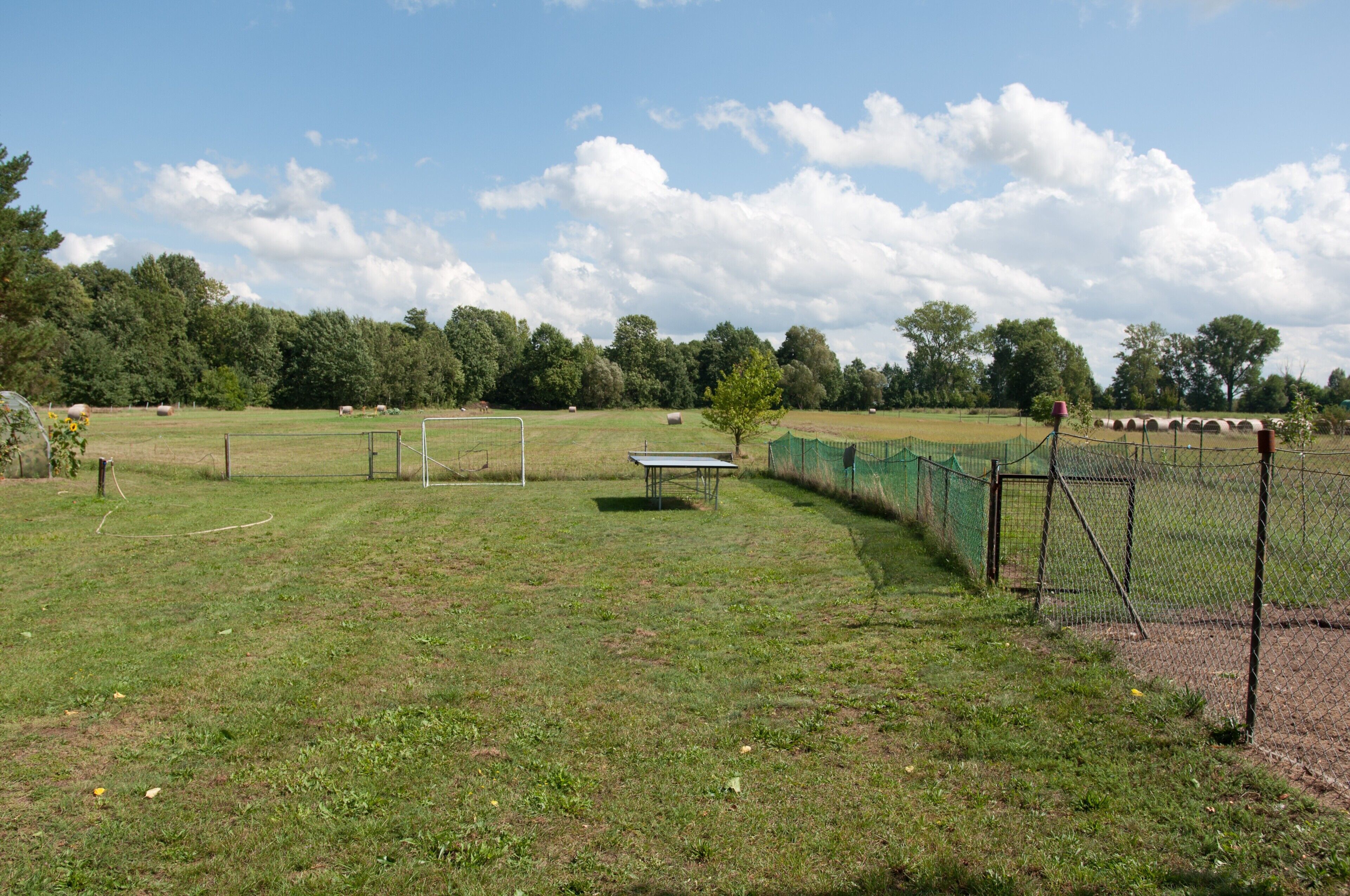Un champ d’herbe avec un but de football, une table et une clôture.