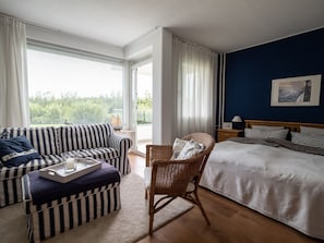 Une chambre à coucher avec un lit, un canapé, une chaise et une fenêtre avec des rideaux.