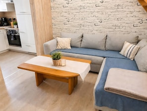 Una sala de estar moderna con un sofá, una mesa de madera y una pared con diseño de ladrillo.