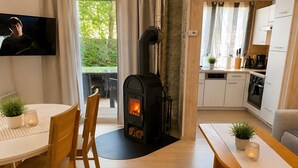 Ein modernes Wohnzimmer mit Kamin, Holzmöbeln, einem Fernseher und einer Küchenzeile.
