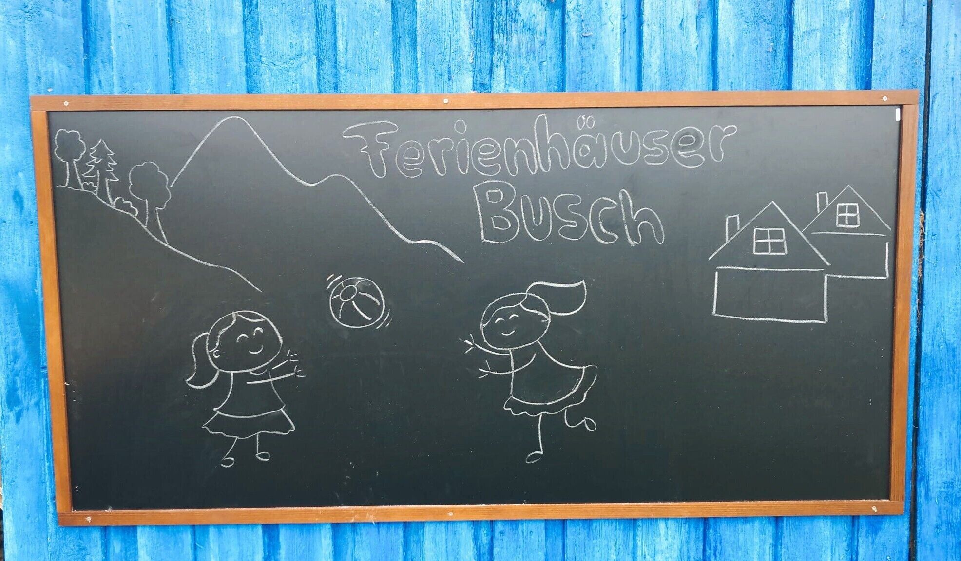Un tableau noir orné de dessins d’enfants, d’une montagne et d’une maison, avec l’inscription « Fetenhäuser Busch ».