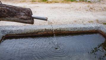 A metal spout pouring water into a rectangular basin.