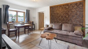 Ett vardagsrum med ett matbord i trä, stolar, en soffa och en vägg med ett mönster.
